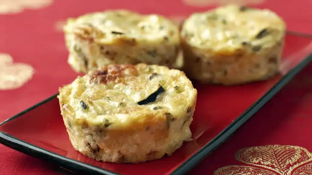 Recette de Flan de courgettes individuels et dorés servis sur une assiette rouge, issus d'une recette facile.