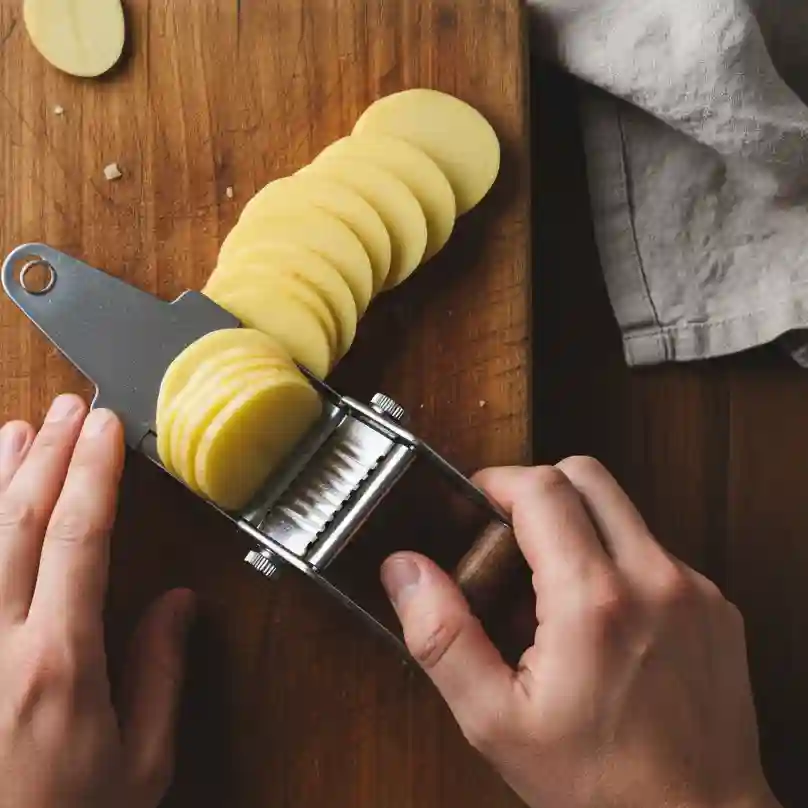 Découpe de pommes de terre en tranches fines et régulières de 3-4mm avec une mandoline pour gratin dauphinois