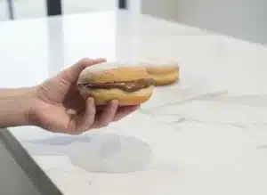 Beignets au Four Ultra Moelleux : La Recette Facile (Sans Friture) 9 Garnir généreusement un beignet au four coupé en deux avec de la pâte à tartiner au chocolat.