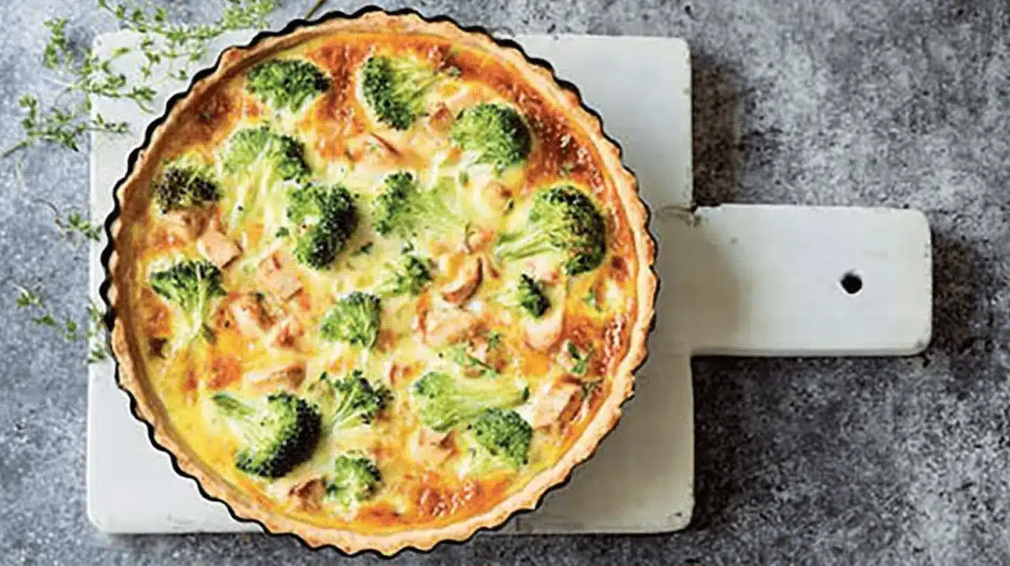 Home page 5 Délicieuse quiche poulet brocoli au four, joliment présentée avec une croûte dorée et des herbes fraîches.